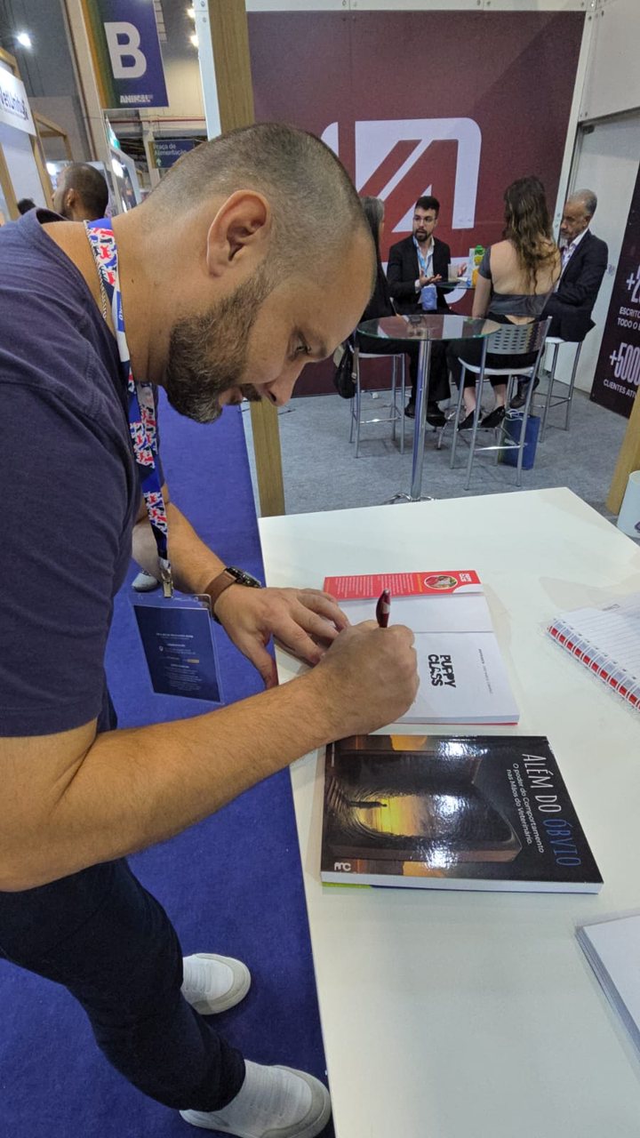 João Marcel Camargo autografando um livro em um estande de feira